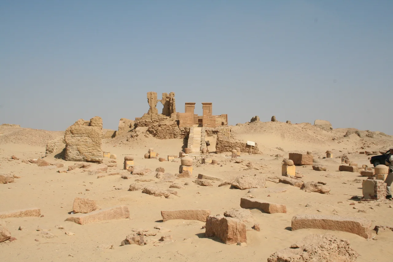 Vestiges de bâtiments et escalier de pierre au milieu des ruines sableuses de Karanis.