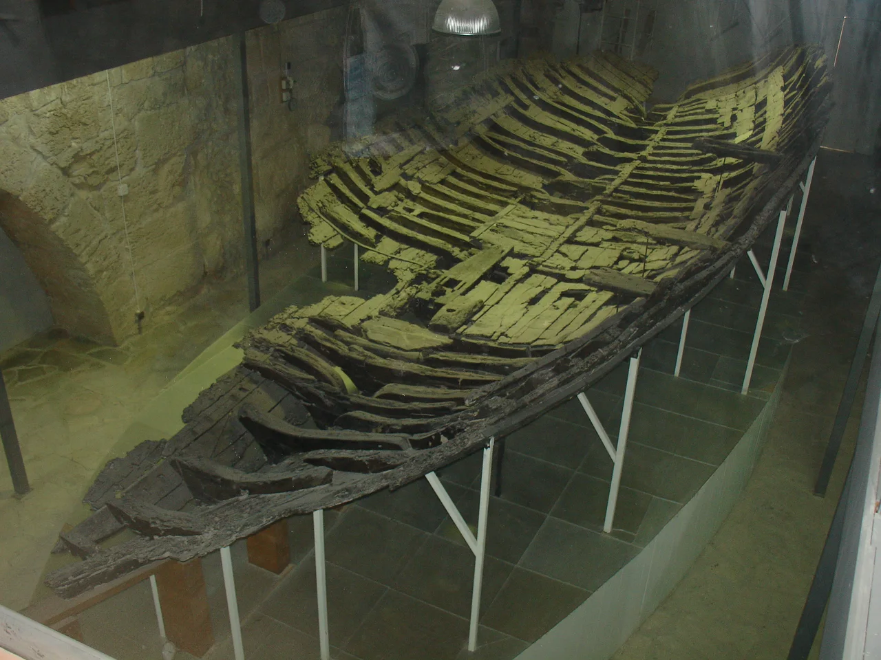 Coque en bois de l’épave de Kyrenia soutenue par une armature dans un musée.